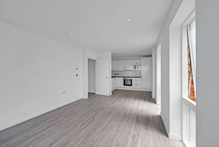 A modern, unfurnished apartment with an open-plan living area and kitchen.