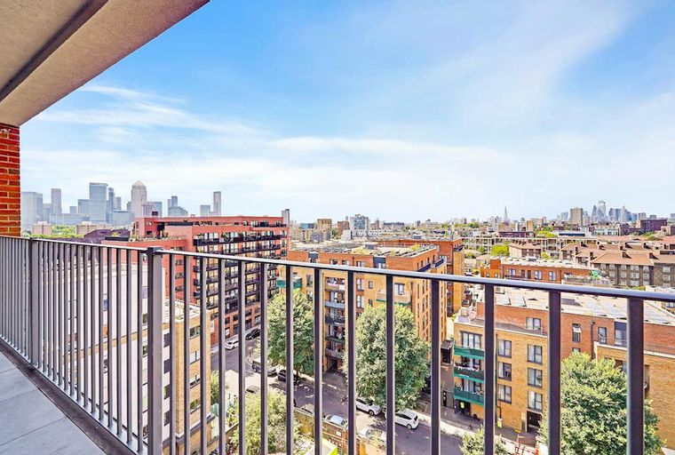 A view of a city skyline from a balcony with a railing.