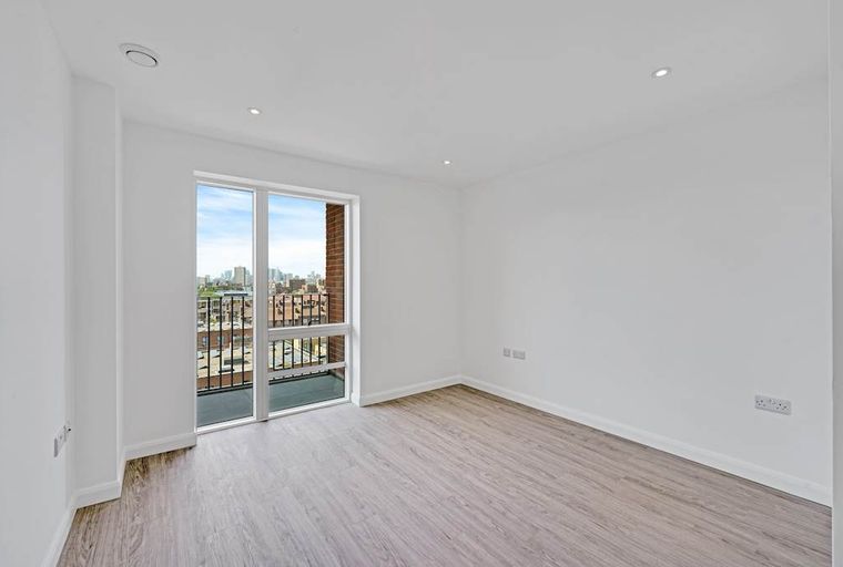 A room with a large window and a balcony overlooking a city.