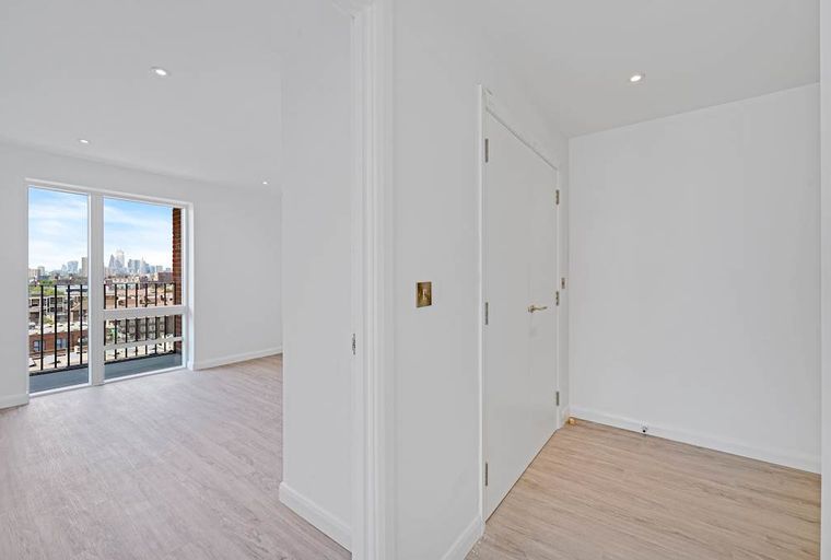 A hallway and a room with a large window overlooking a city skyline.