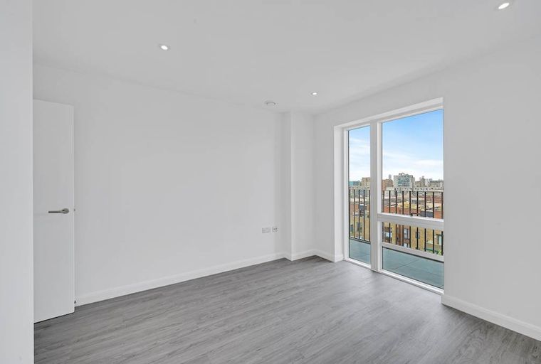 A vacant room with a door, large window, and grey flooring.