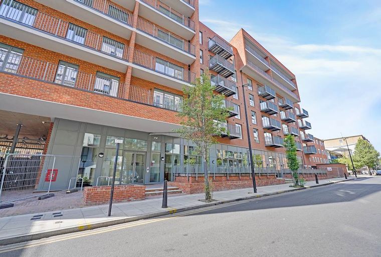 A modern brick apartment building with balconies and large glass windows on the ground floor.