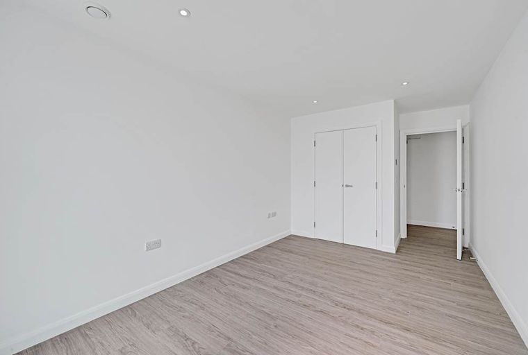 A room with white walls, light wood flooring, and two doors.