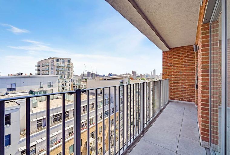 A balcony overlooking a cityscape with multiple buildings under a blue sky.