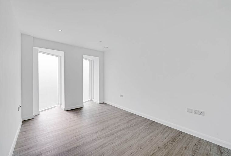 A room with two frosted windows and a grey wood-effect floor.