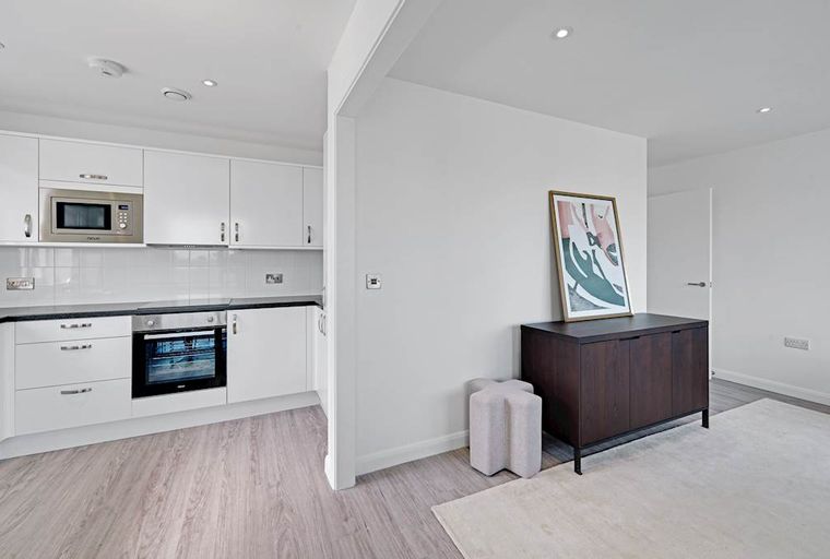 A modern kitchen and living area with a dark wood cabinet and abstract art.