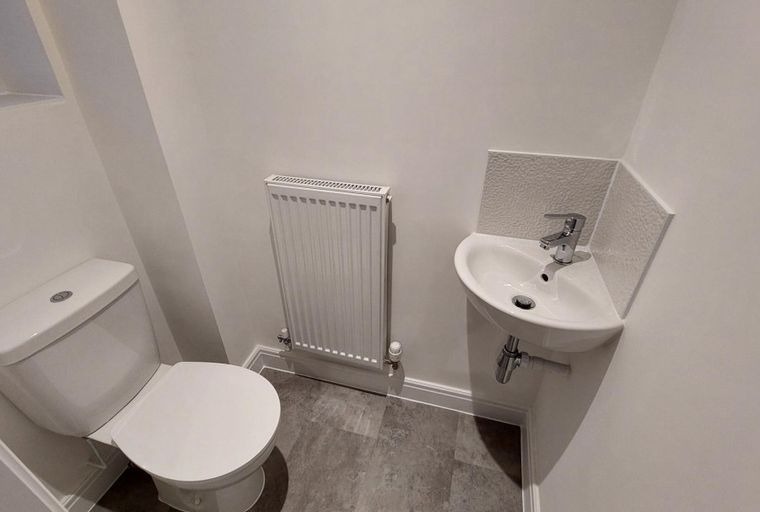 A toilet and a corner sink with a faucet in a bathroom.