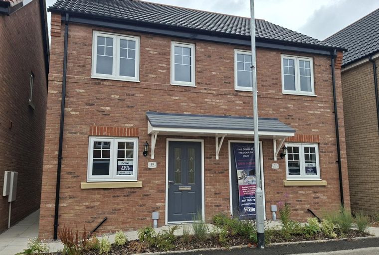 A brick house with white windows and a grey front door.