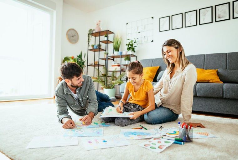 A family drawing together on the floor in a living room.