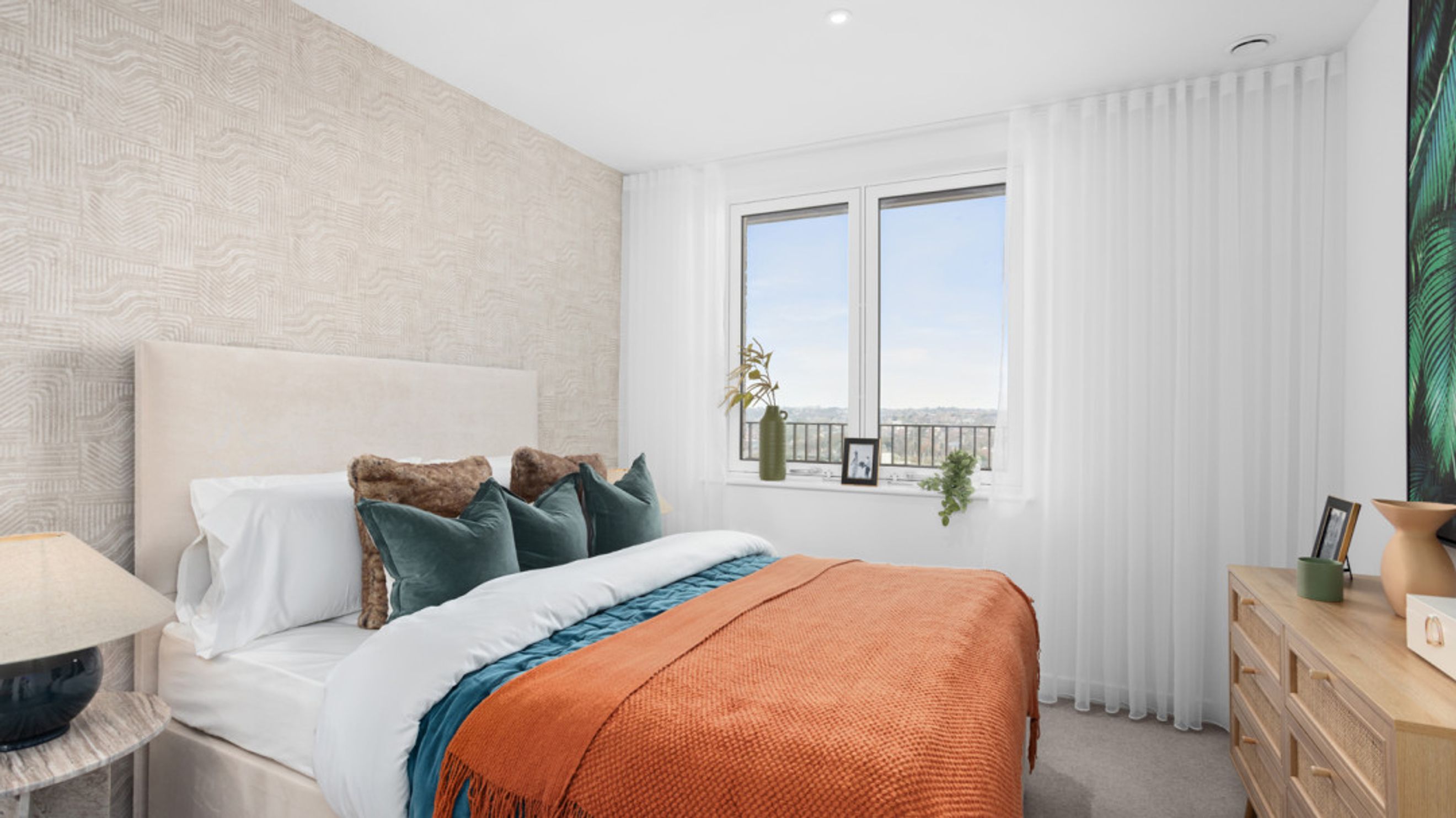 A bedroom with a bed, pillows, a dresser, and a window.