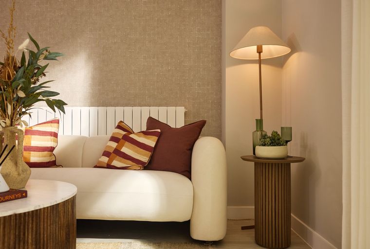 A living room with a white sofa, accent pillows, a dried floral arrangement, and a floor lamp.