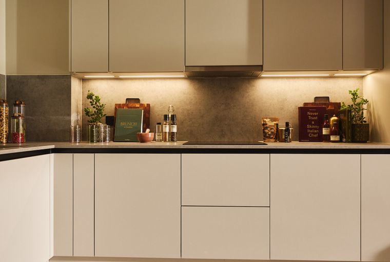 A modern kitchen with light-colored cabinets and a grey backsplash.
