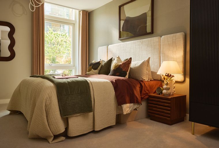 A bedroom with a bed, pillows, a nightstand, and a wardrobe.