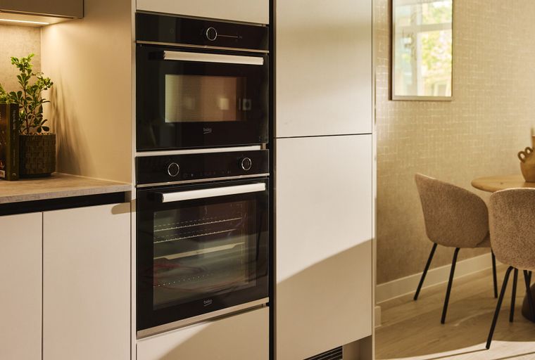A modern kitchen with integrated ovens and a dining area with chairs and a table.