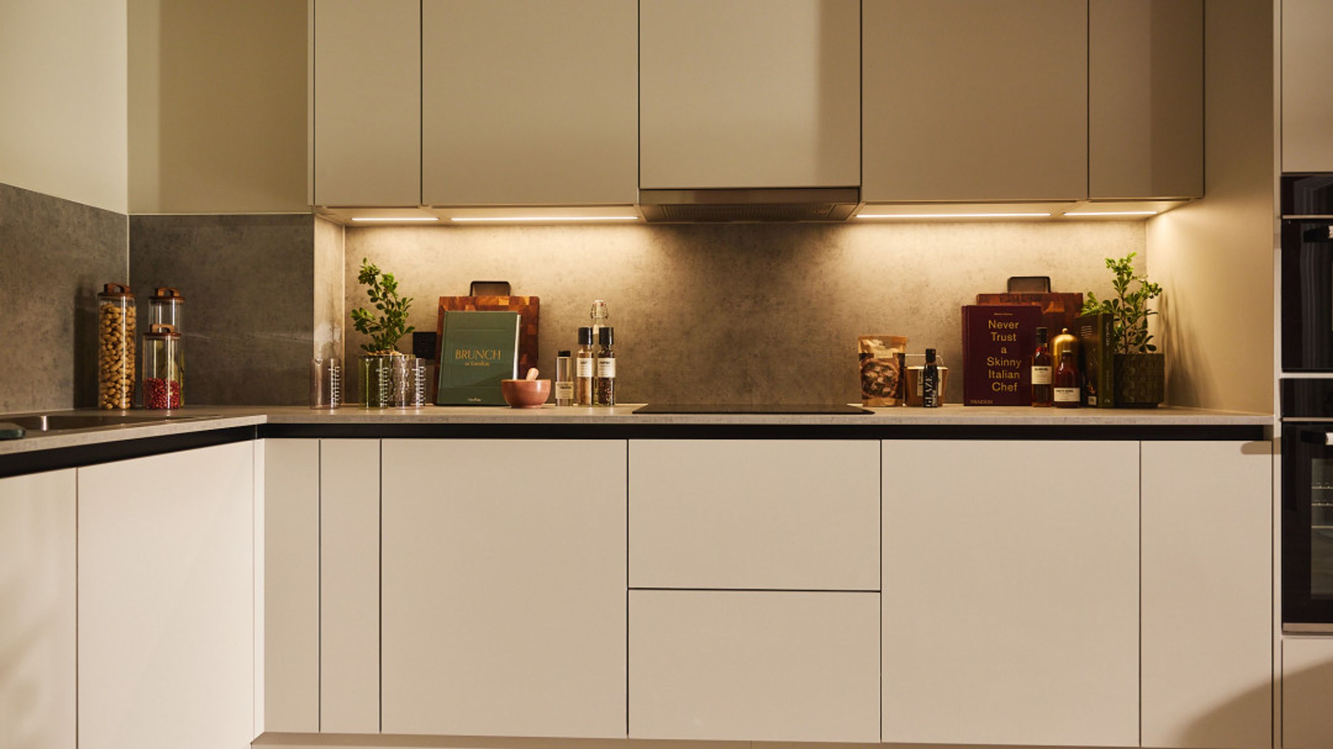 A modern kitchen with light-colored cabinets and a grey backsplash.