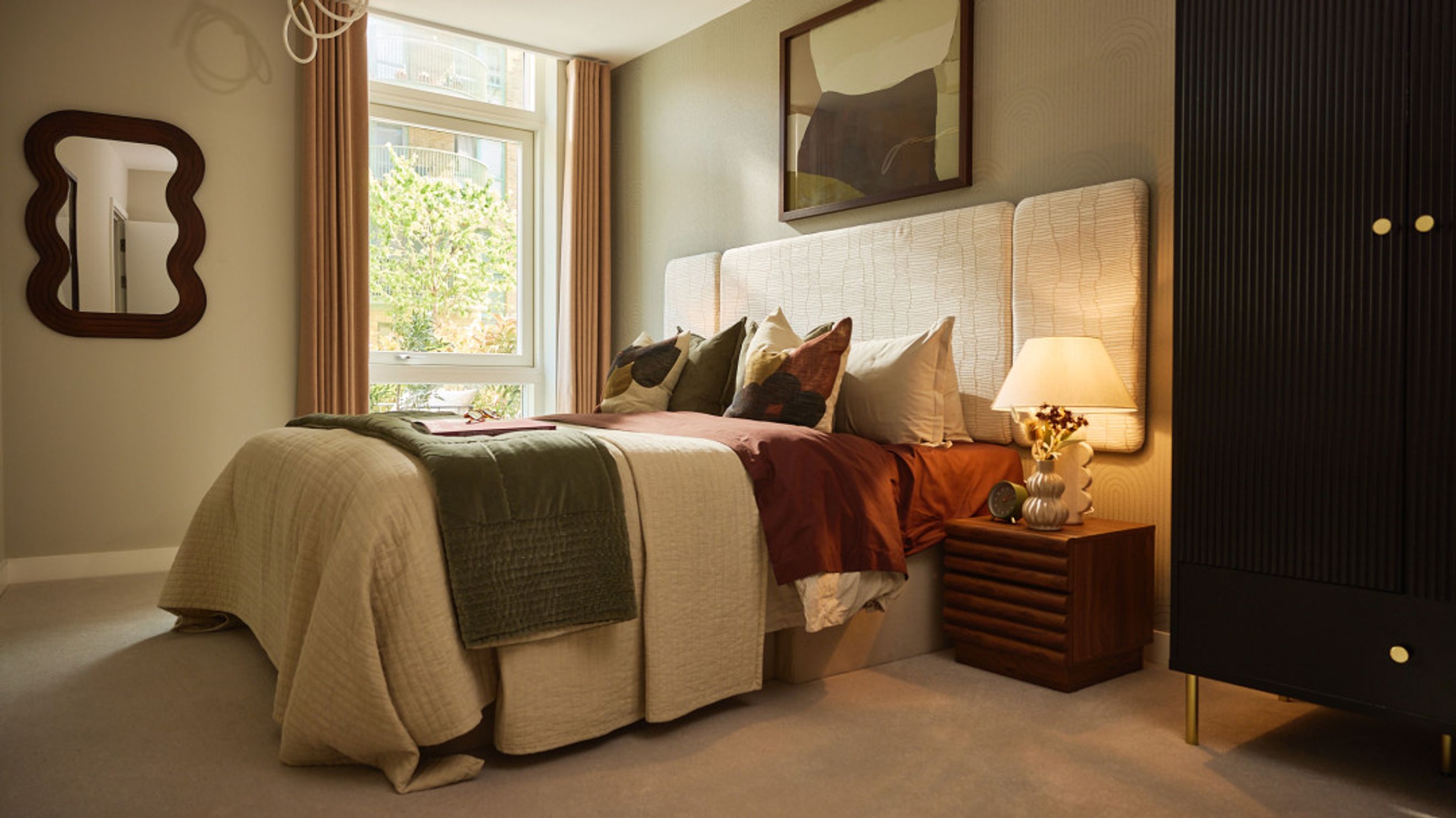 A bedroom with a bed, pillows, a nightstand, and a wardrobe.