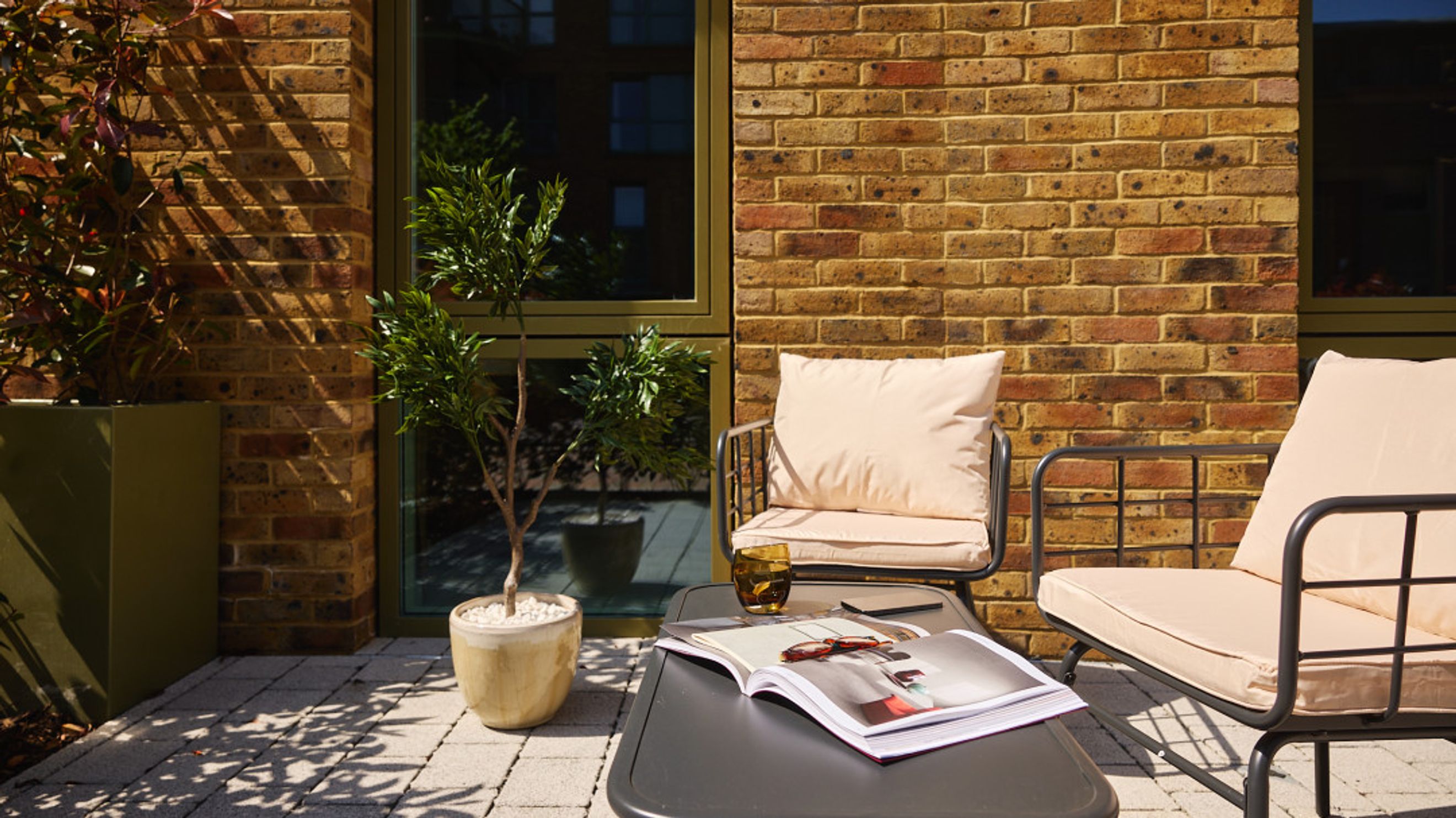 A patio with two chairs, a table, a plant, and a book.
