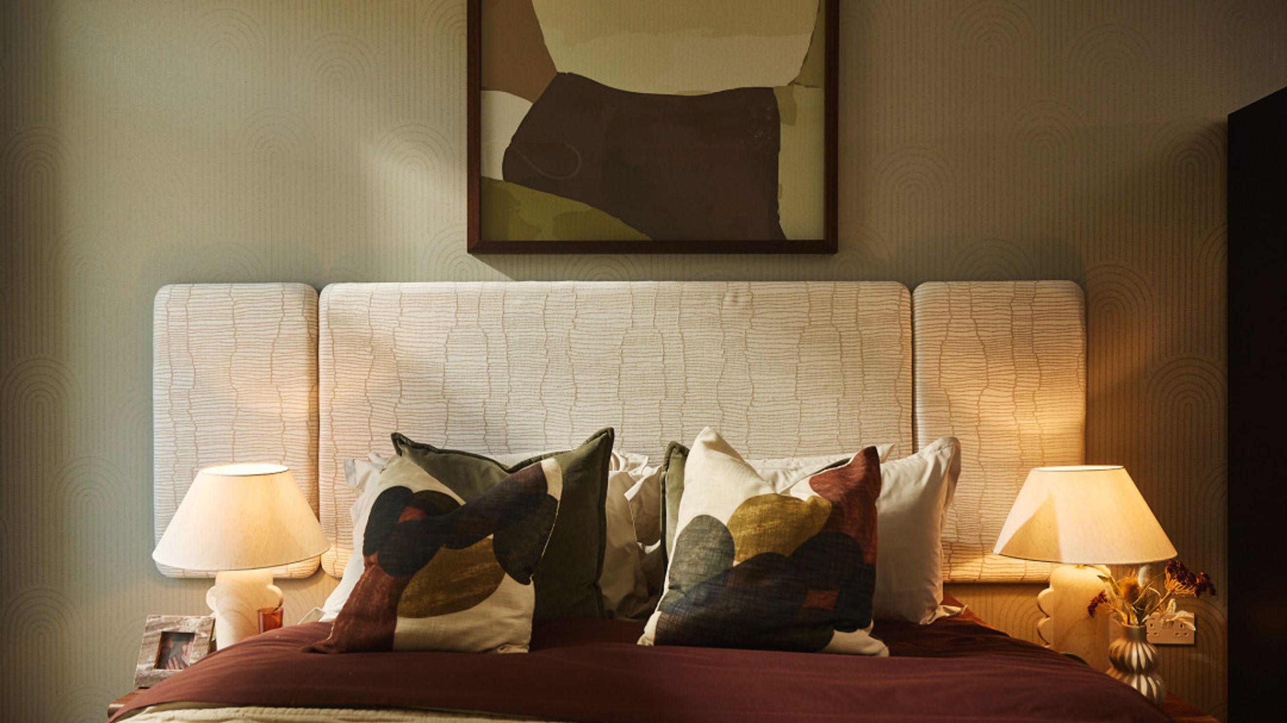 A bedroom with a bed, headboard, pillows, and bedside lamps.
