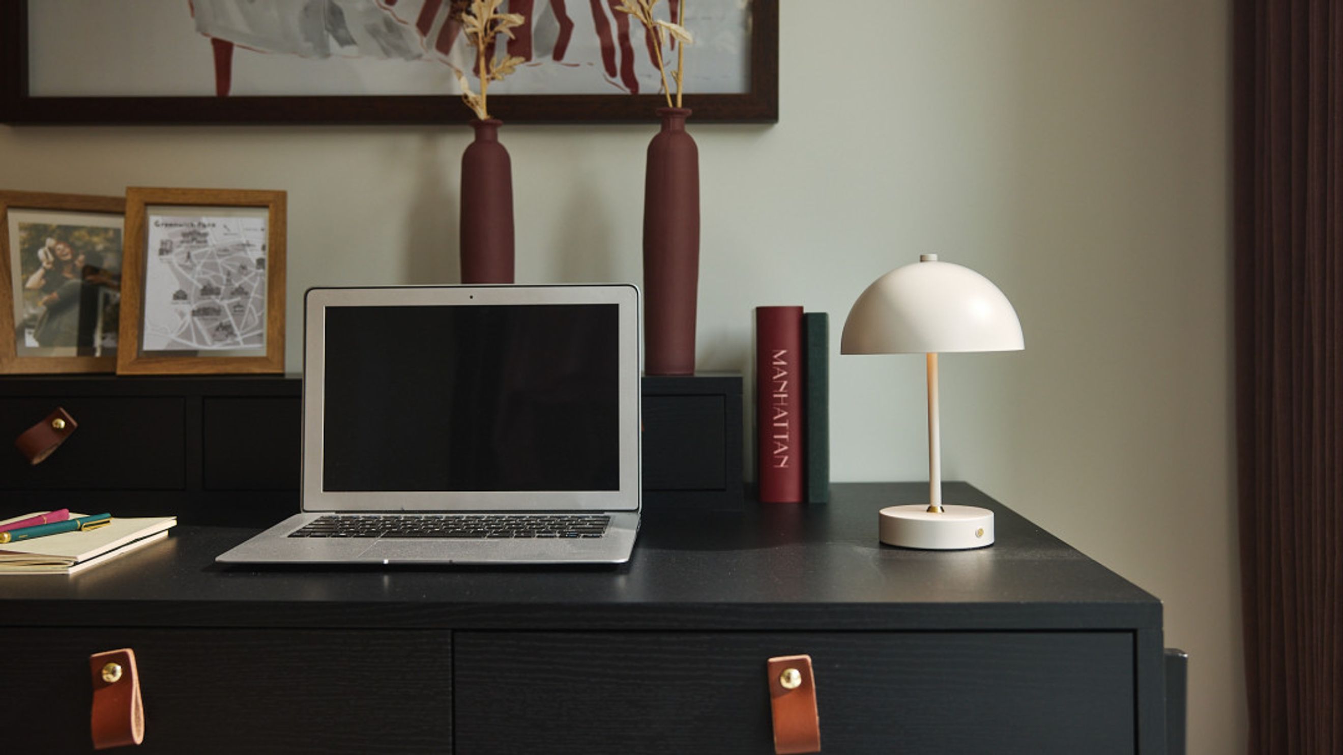 A desk with a laptop, books, and a lamp.