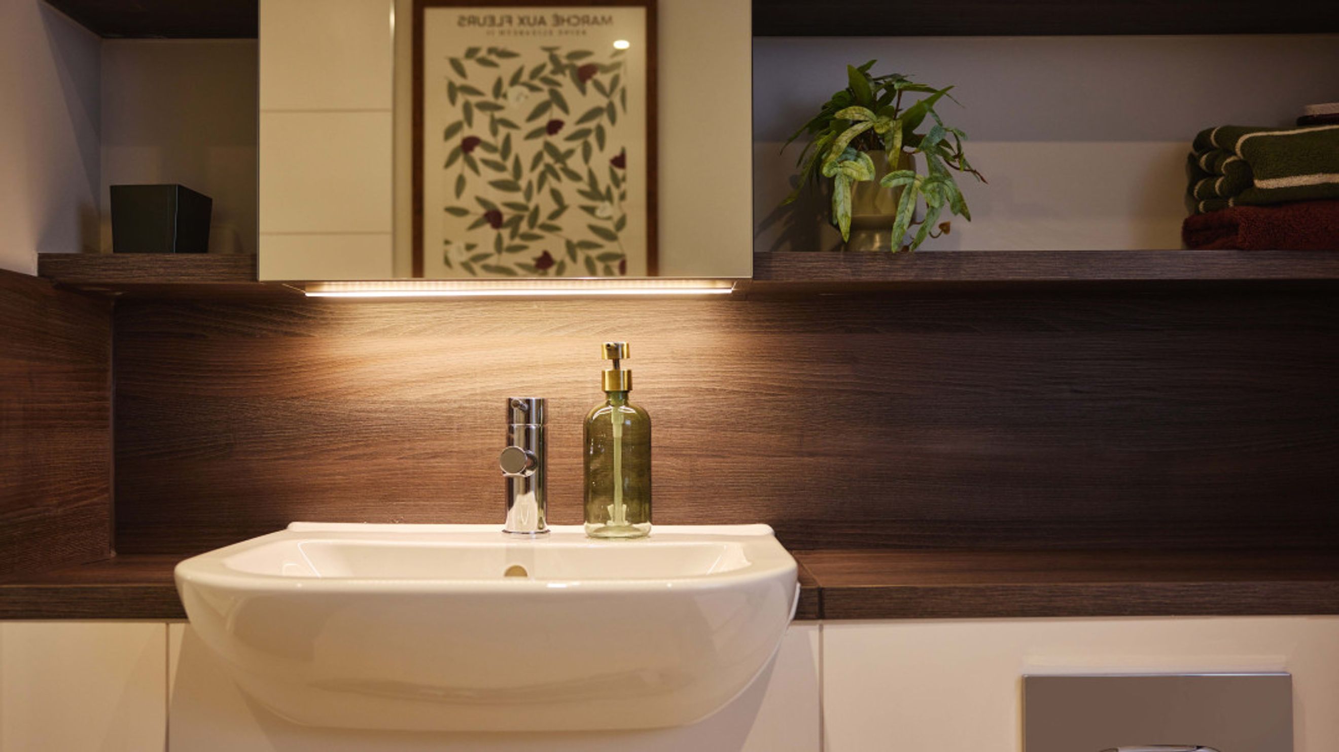 A bathroom sink with a faucet and a soap dispenser, set against a wooden backsplash with shelving above.