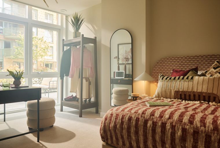 A bedroom with a bed, a vanity, and an open wardrobe.