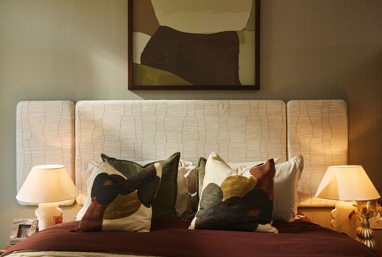 A bedroom with a bed, headboard, pillows, and bedside lamps.