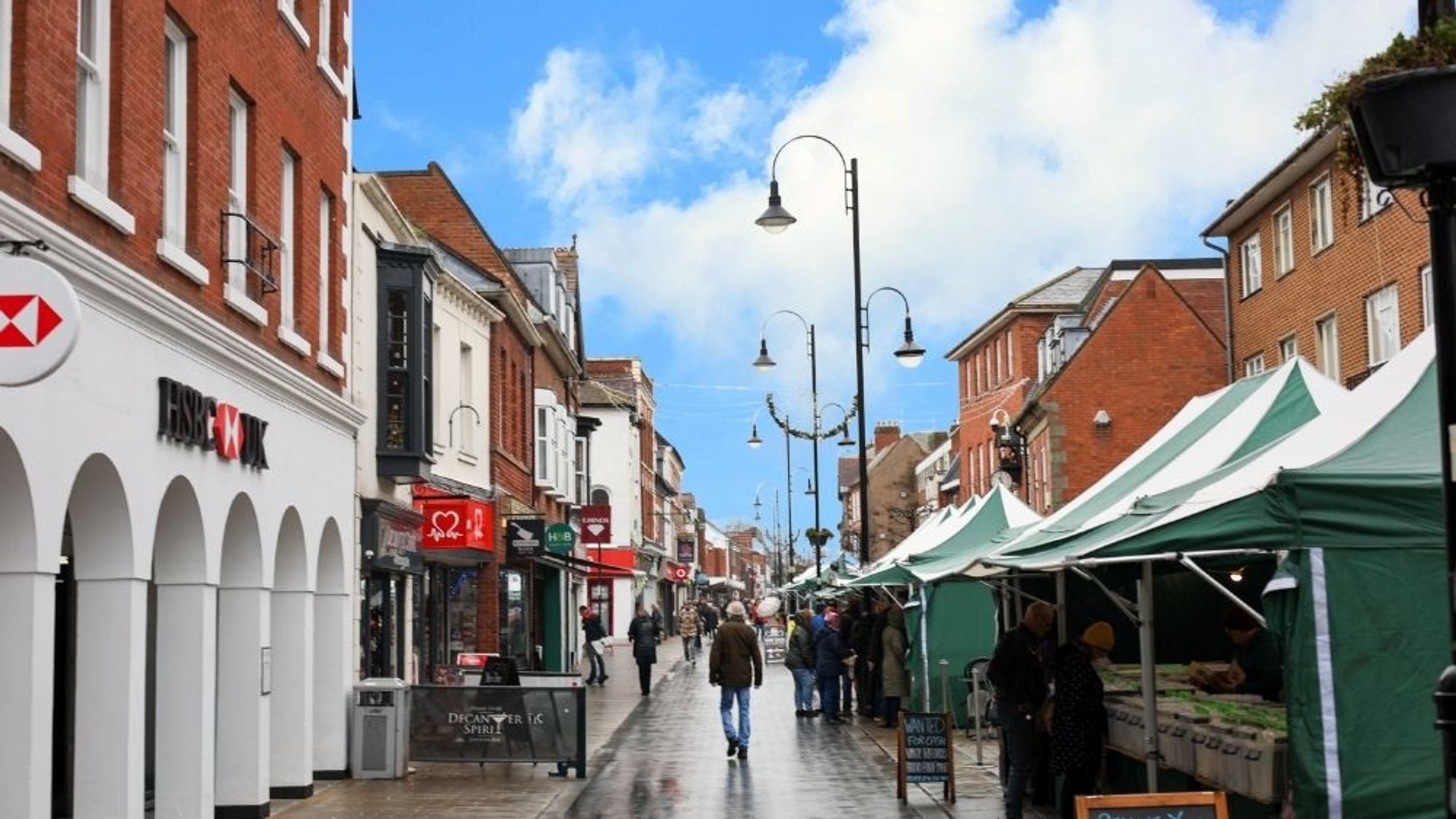 A street scene with shops and market stalls on a cloudy day.