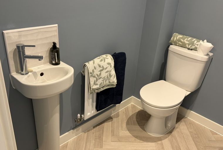 A bathroom with a sink, a toilet, and a radiator with towels.