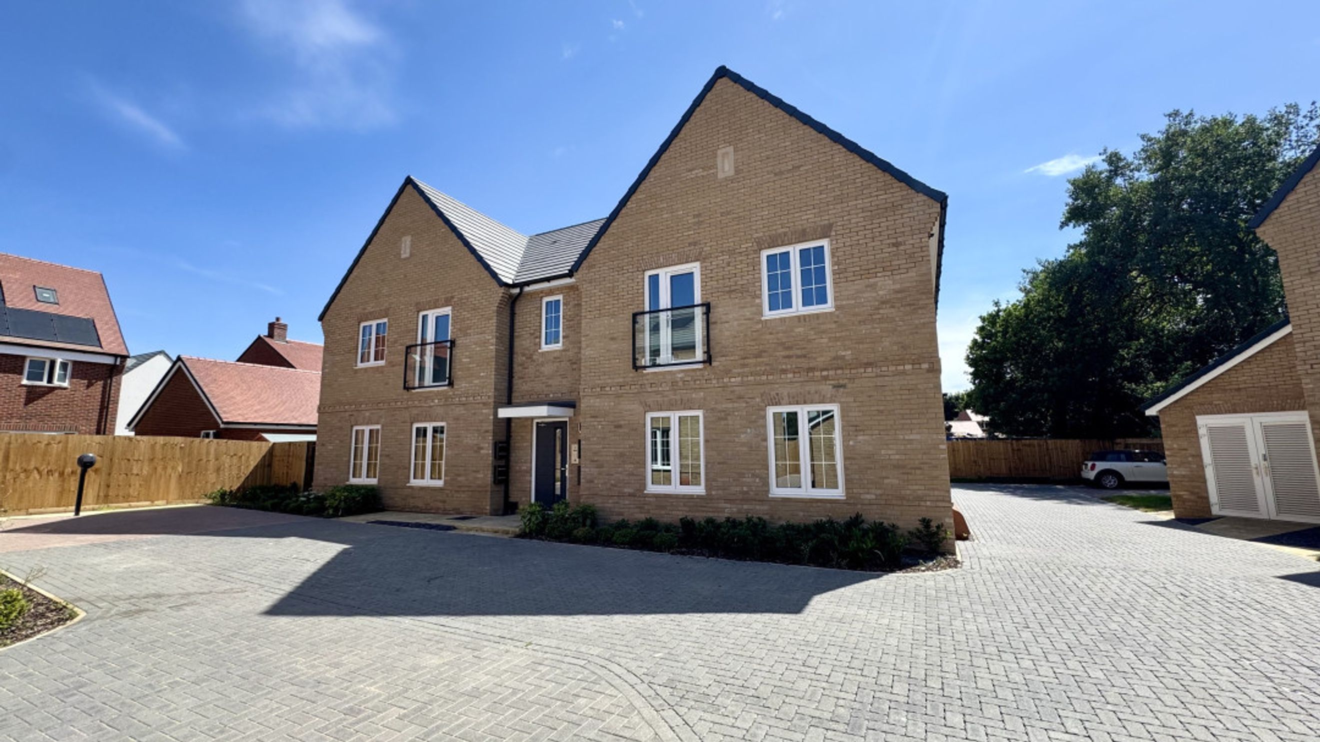 A modern brick building with white-framed windows and a paved driveway.