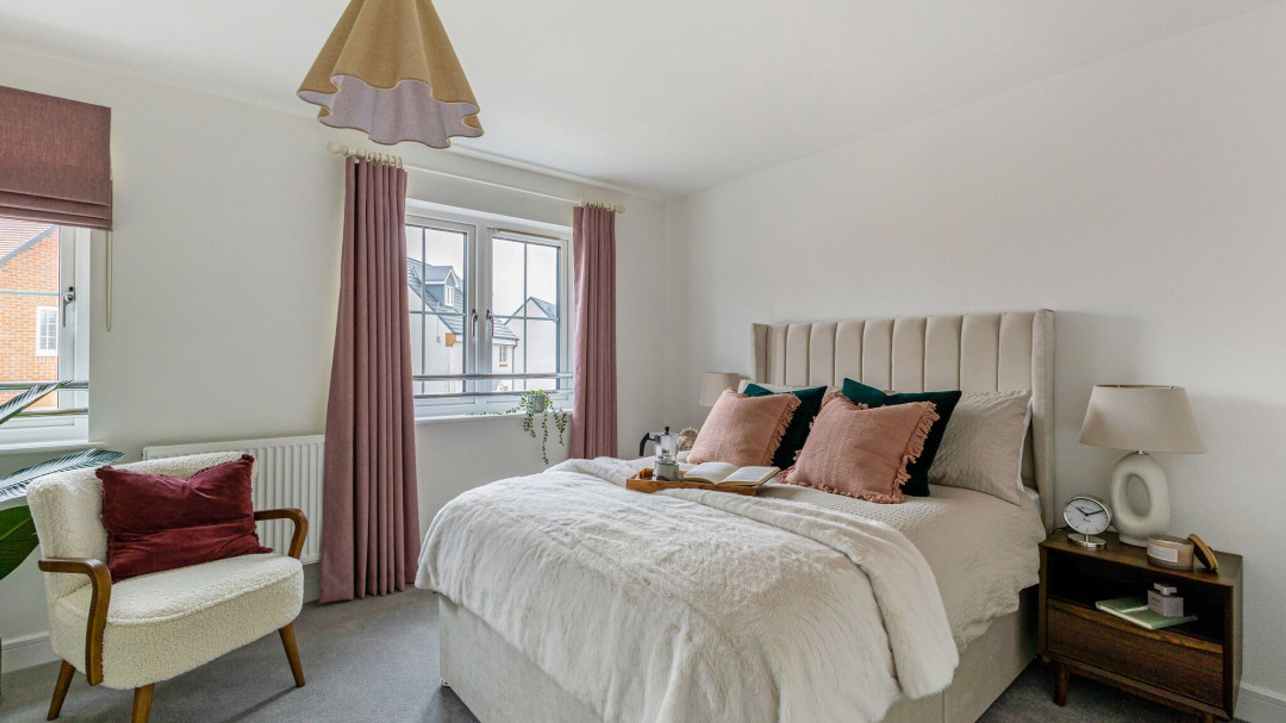 A bedroom with a bed, pillows, curtains, a window, and a chair.