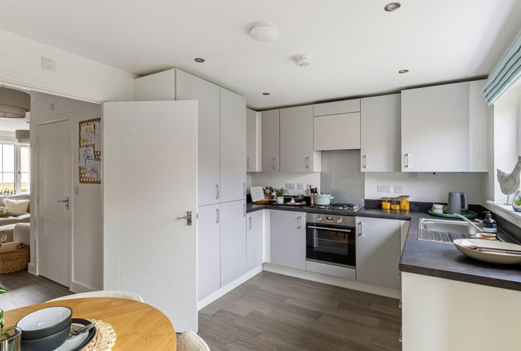 A modern kitchen with white cabinets, a dark countertop, and a built-in oven.