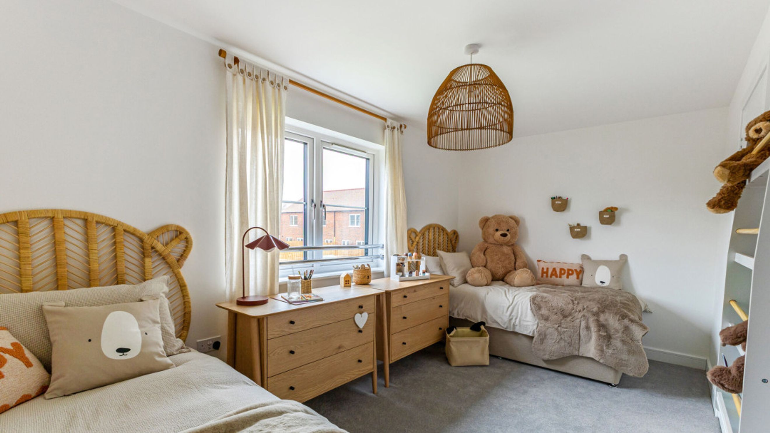 A children's bedroom with two beds, dressers, and teddy bears.