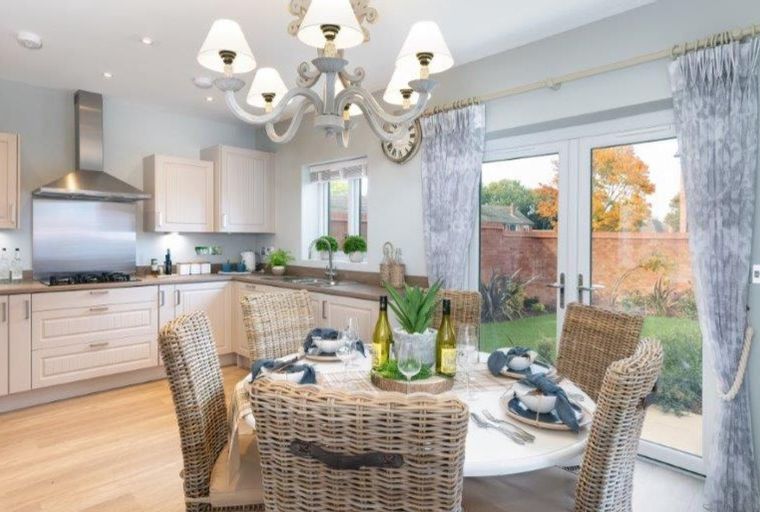 A kitchen and dining area with wicker chairs around a table, a stove, and cabinets.