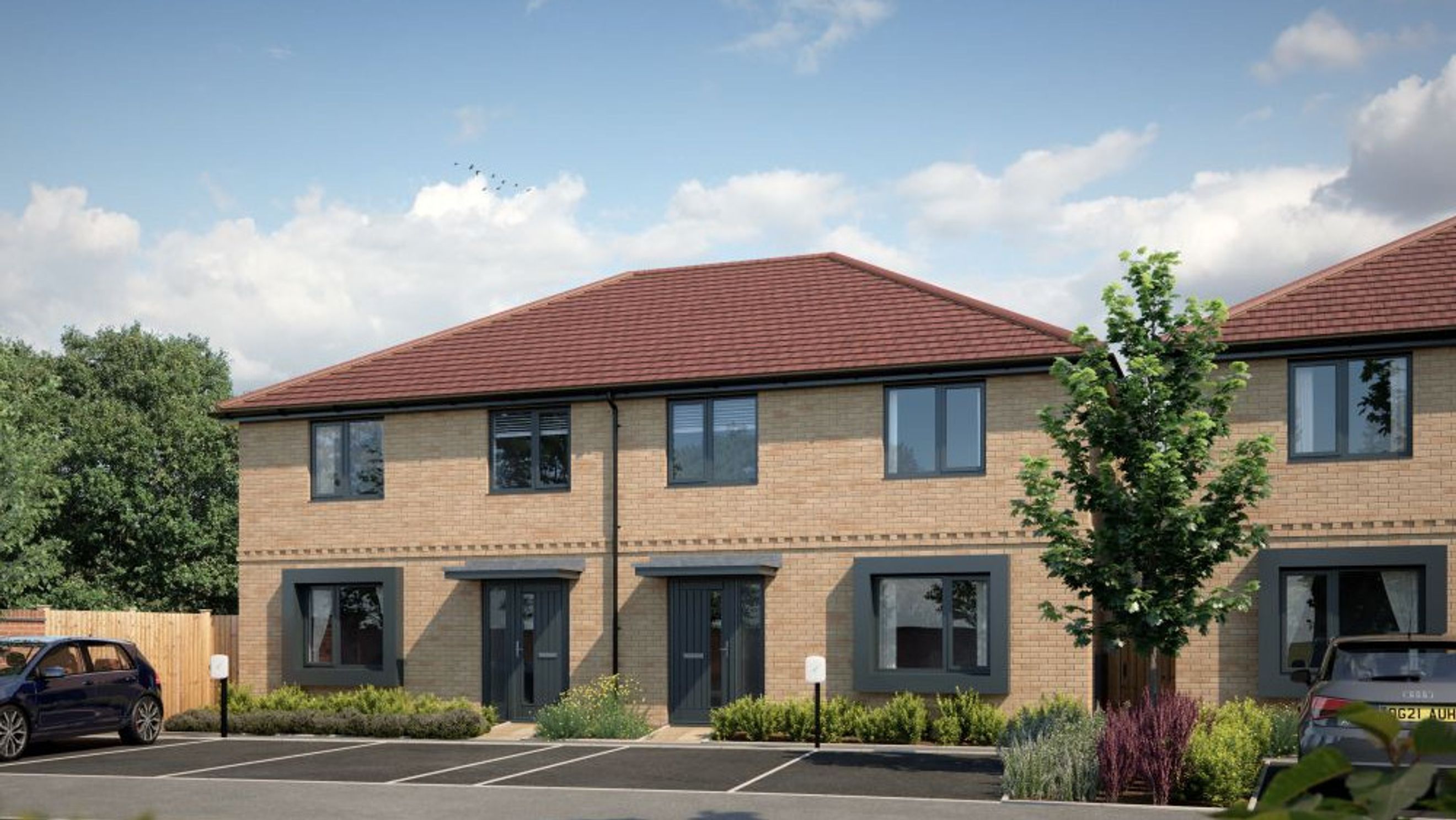 A row of modern brick townhouses with red tile roofs and dark grey windows and doors.