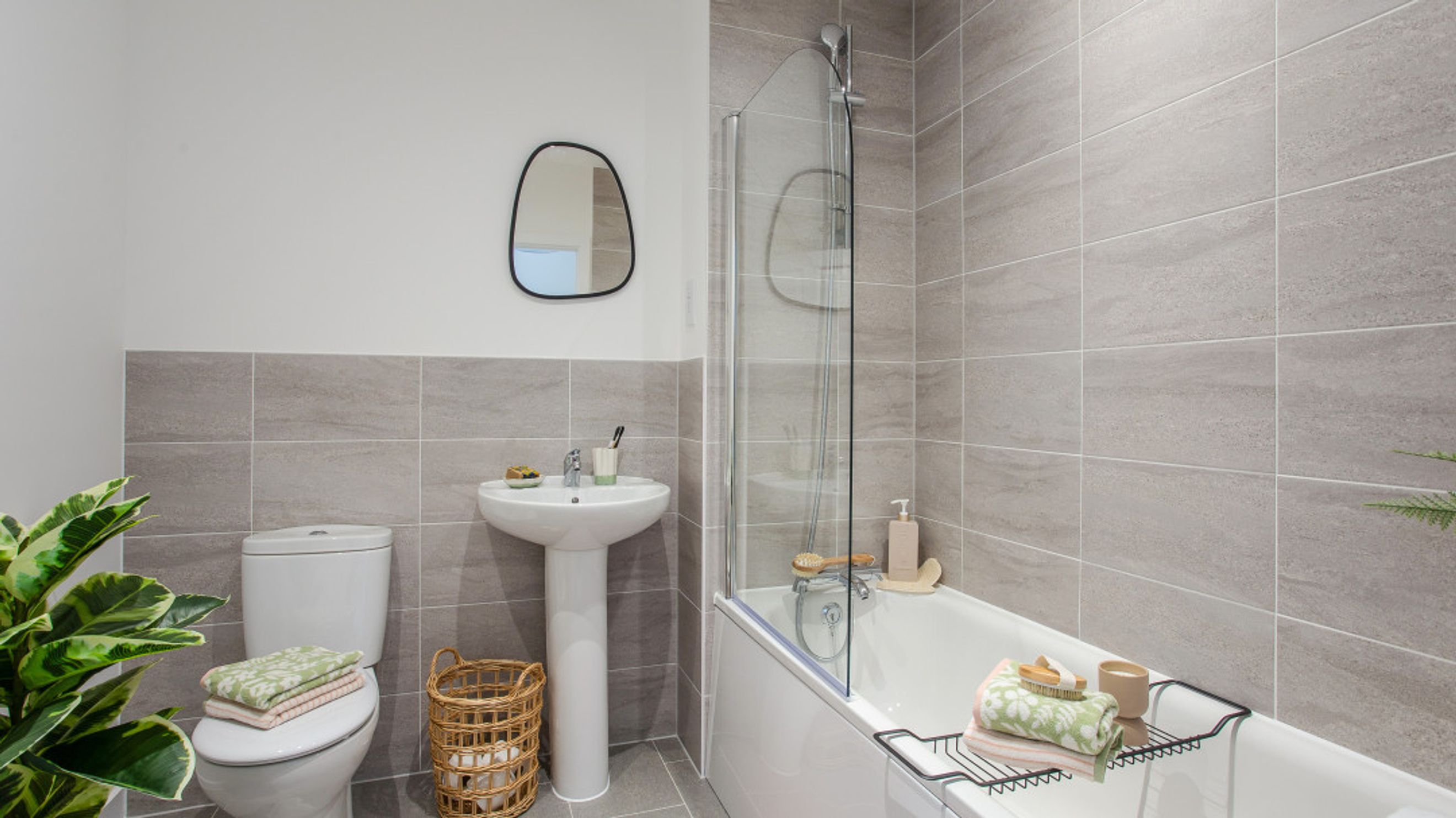 A bathroom with a toilet, sink, bathtub, and mirror.