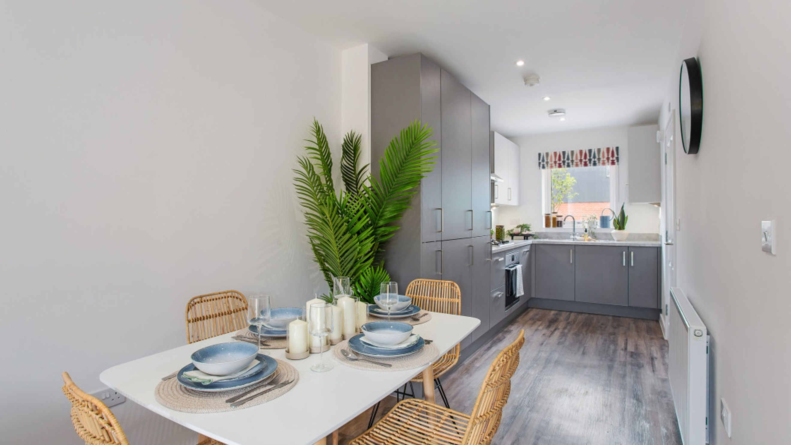 A dining table set for a meal in front of a modern kitchen.
