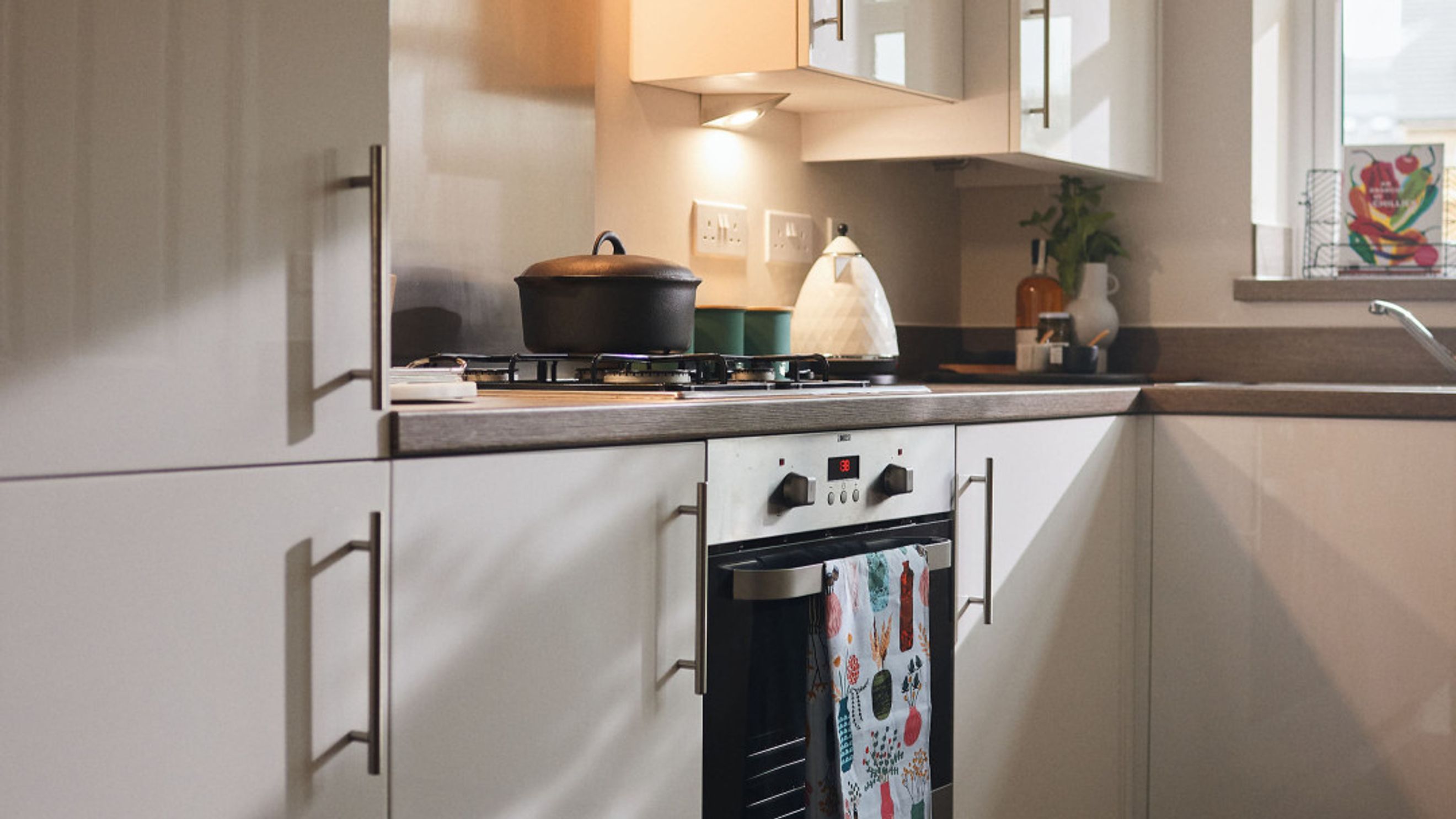 A kitchen with a gas hob, oven, and cabinets.