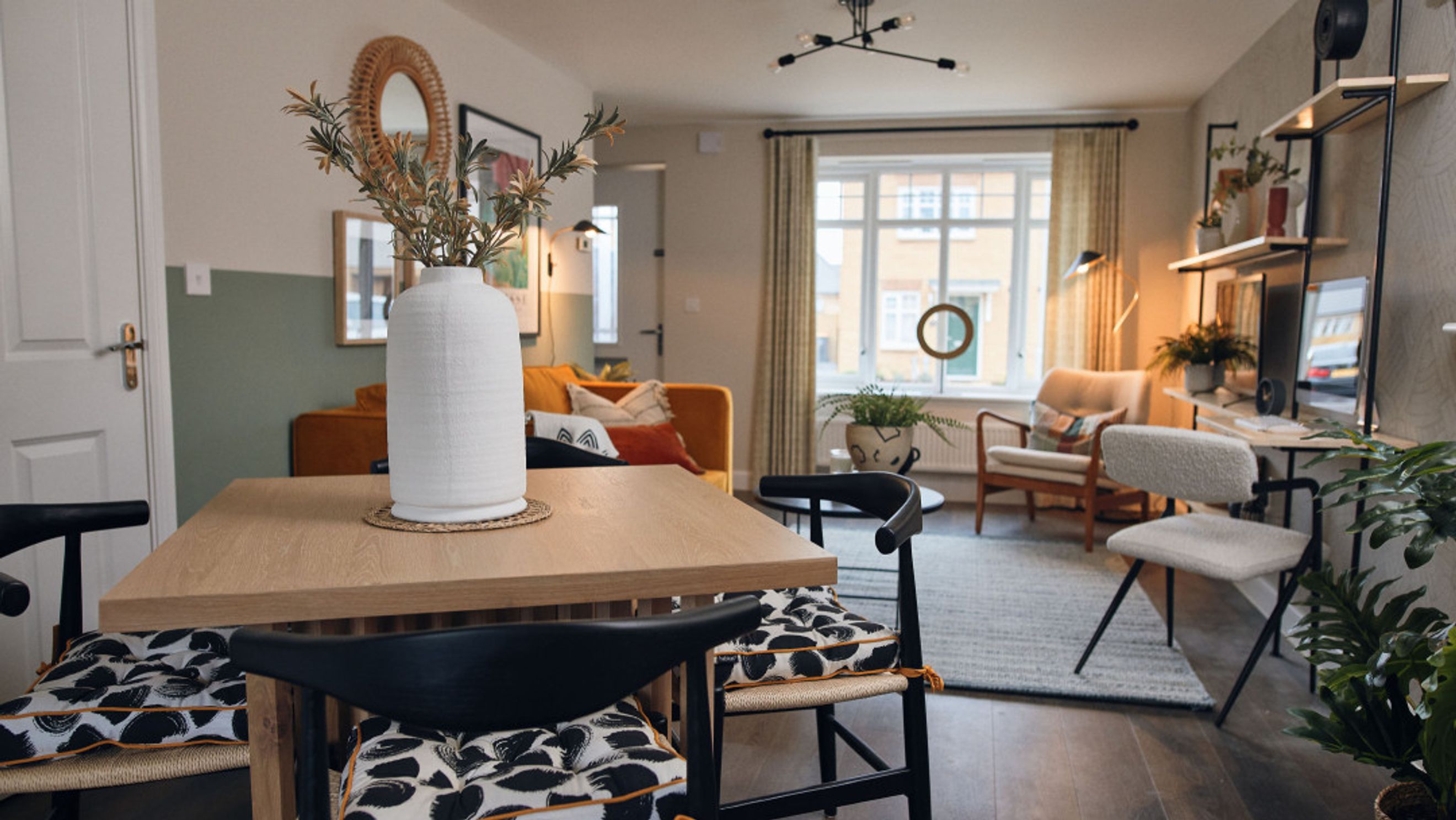 A dining area and living room with a table, chairs, sofa, and window.