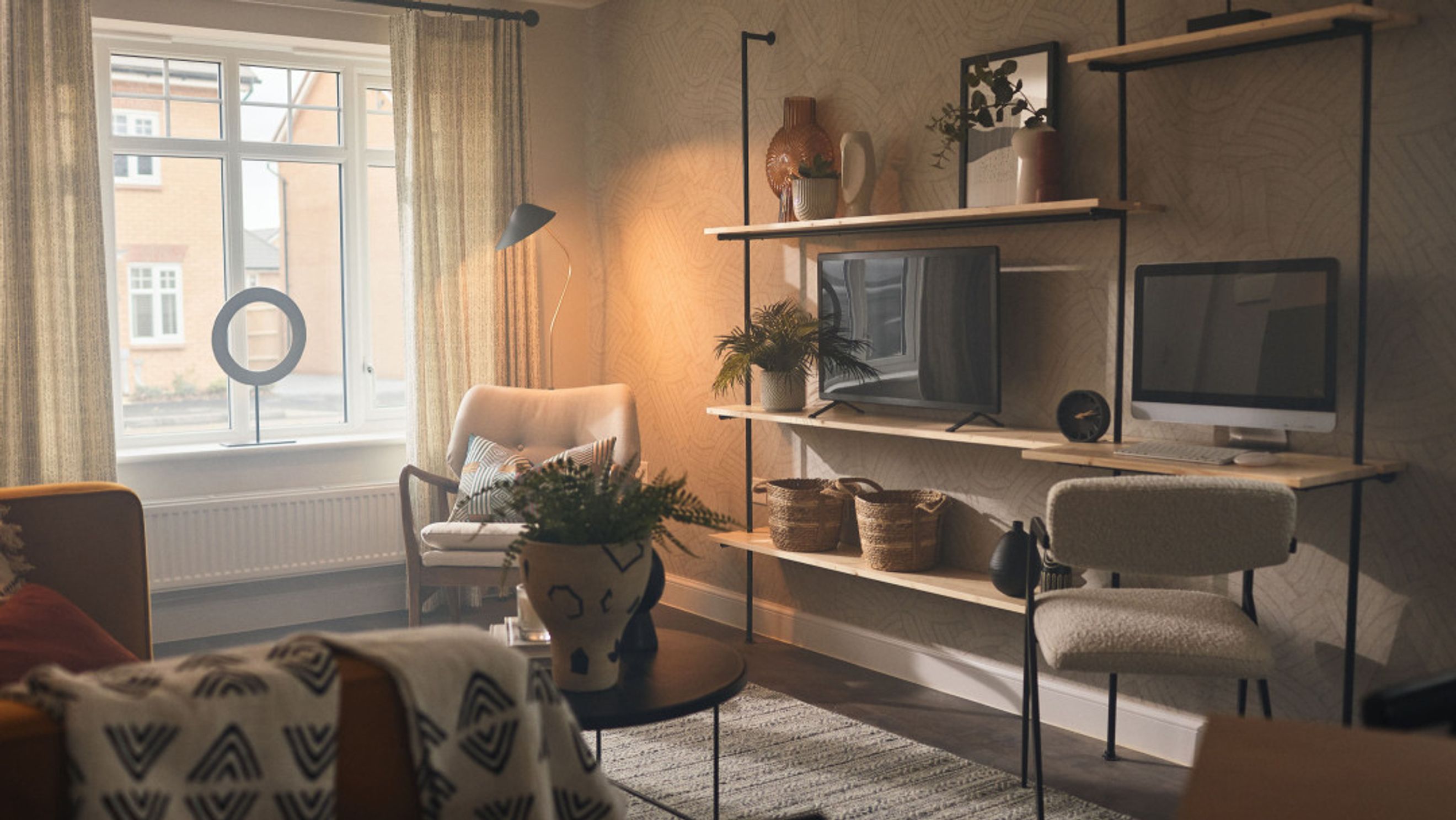 A living room with a chair, a television, a computer, and a shelving unit.