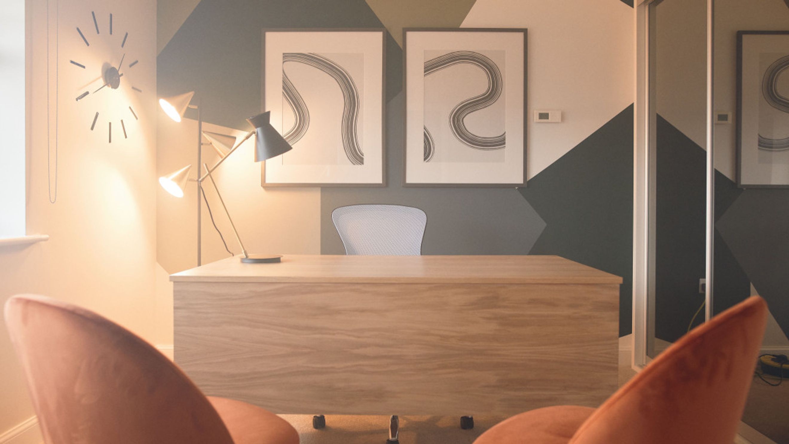 A home office with a wooden desk, chairs, and artwork on the wall.