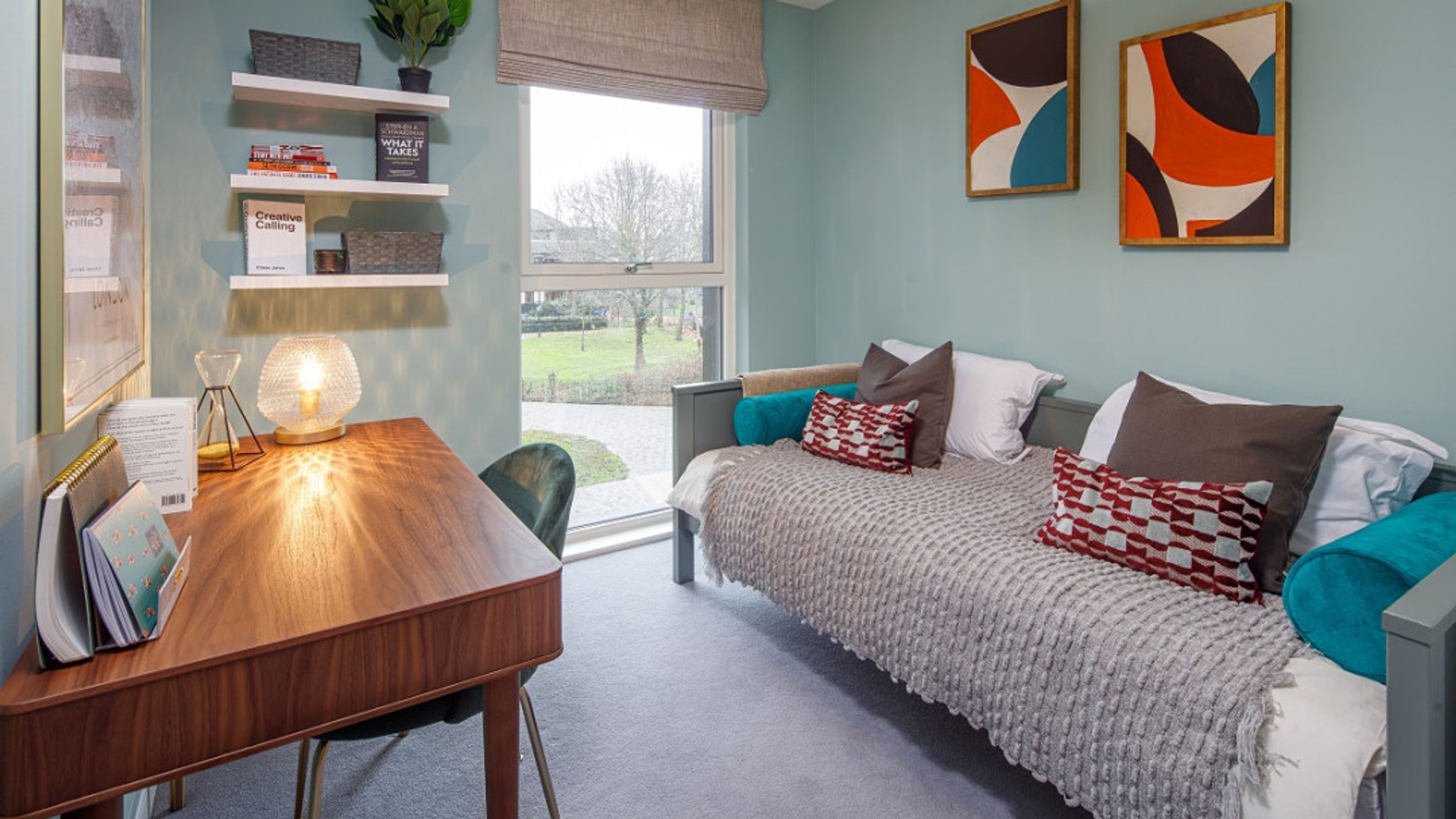 A bedroom with a daybed, desk, and window.