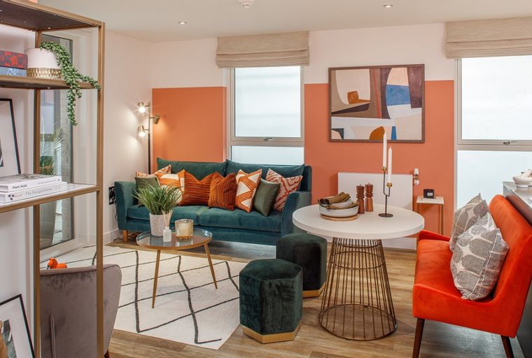 A living room and dining area with a teal sofa, orange seating, and a white dining table.