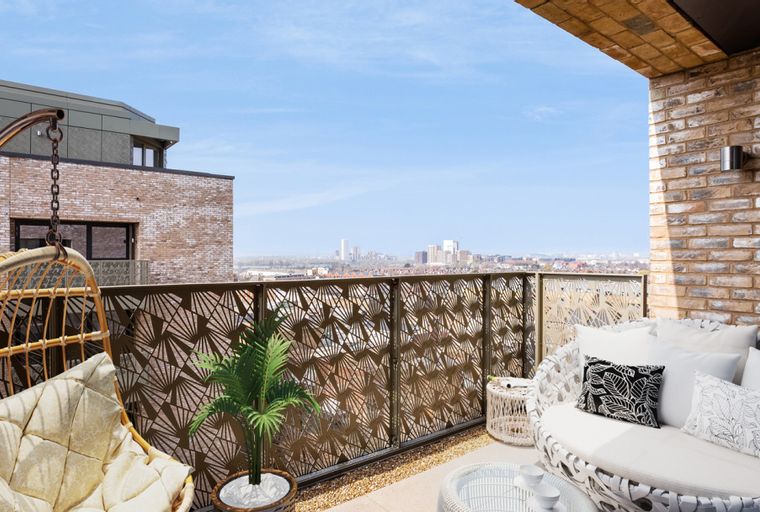 A balcony with a hanging chair, outdoor sofa, and a view of a city skyline.