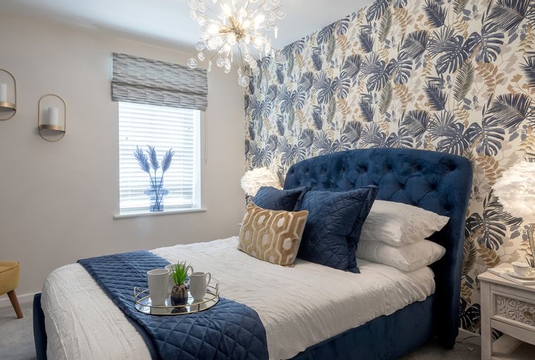 A bedroom with a bed, pillows, a nightstand, a chair, and a window.