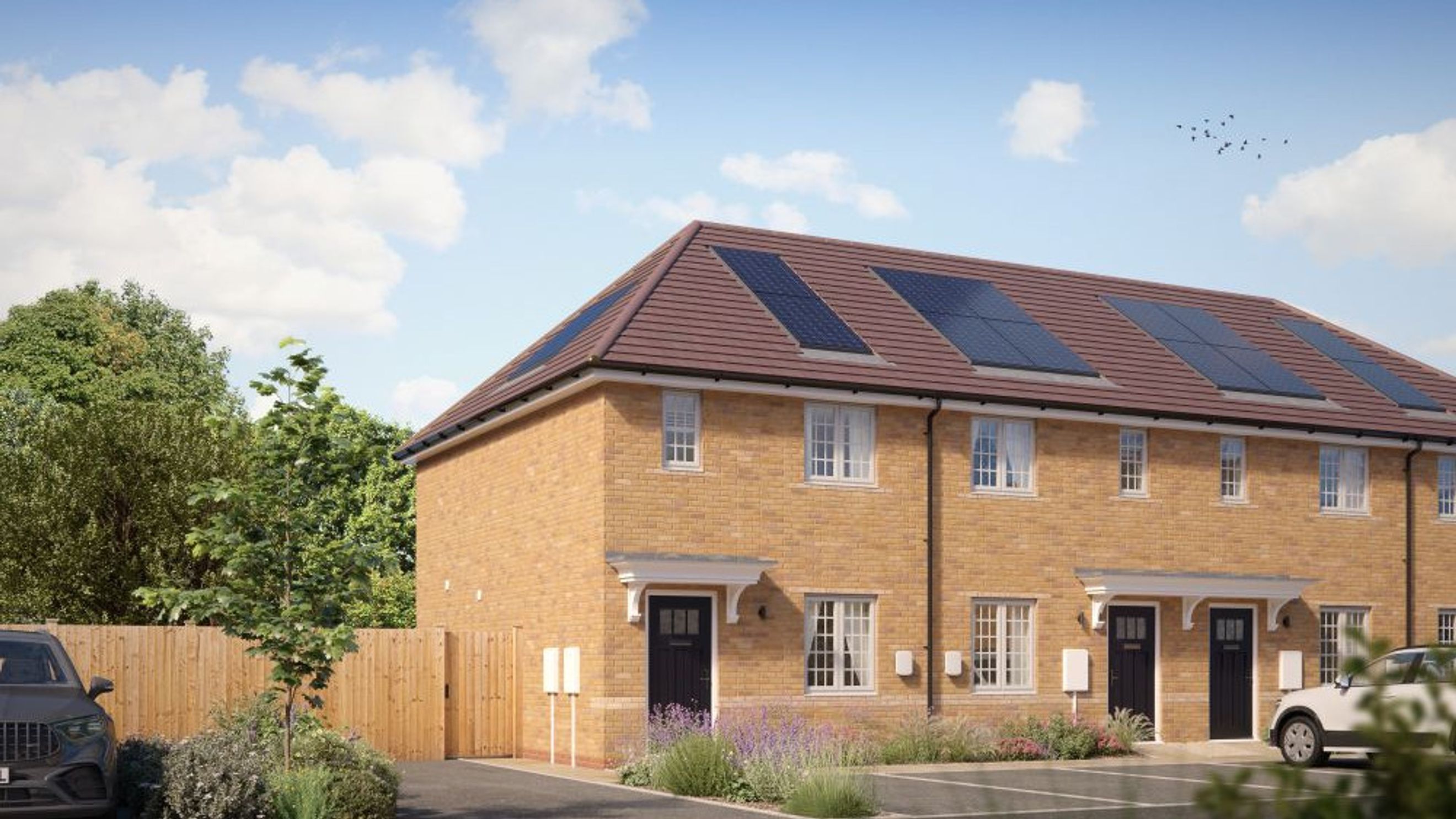 A row of modern brick houses with solar panels on the roof, a driveway, and landscaping.