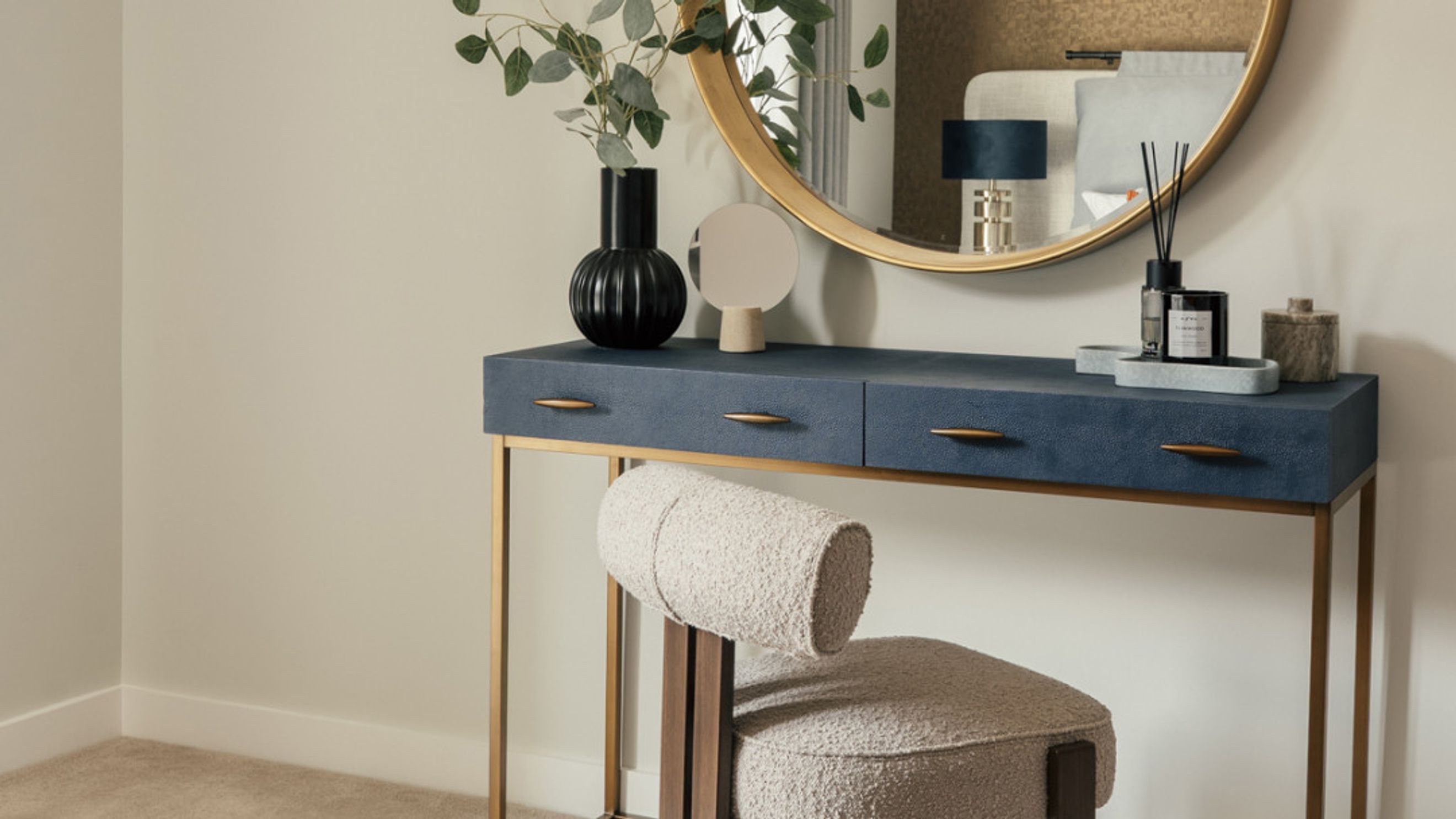 A vanity table with a mirror and a stool.