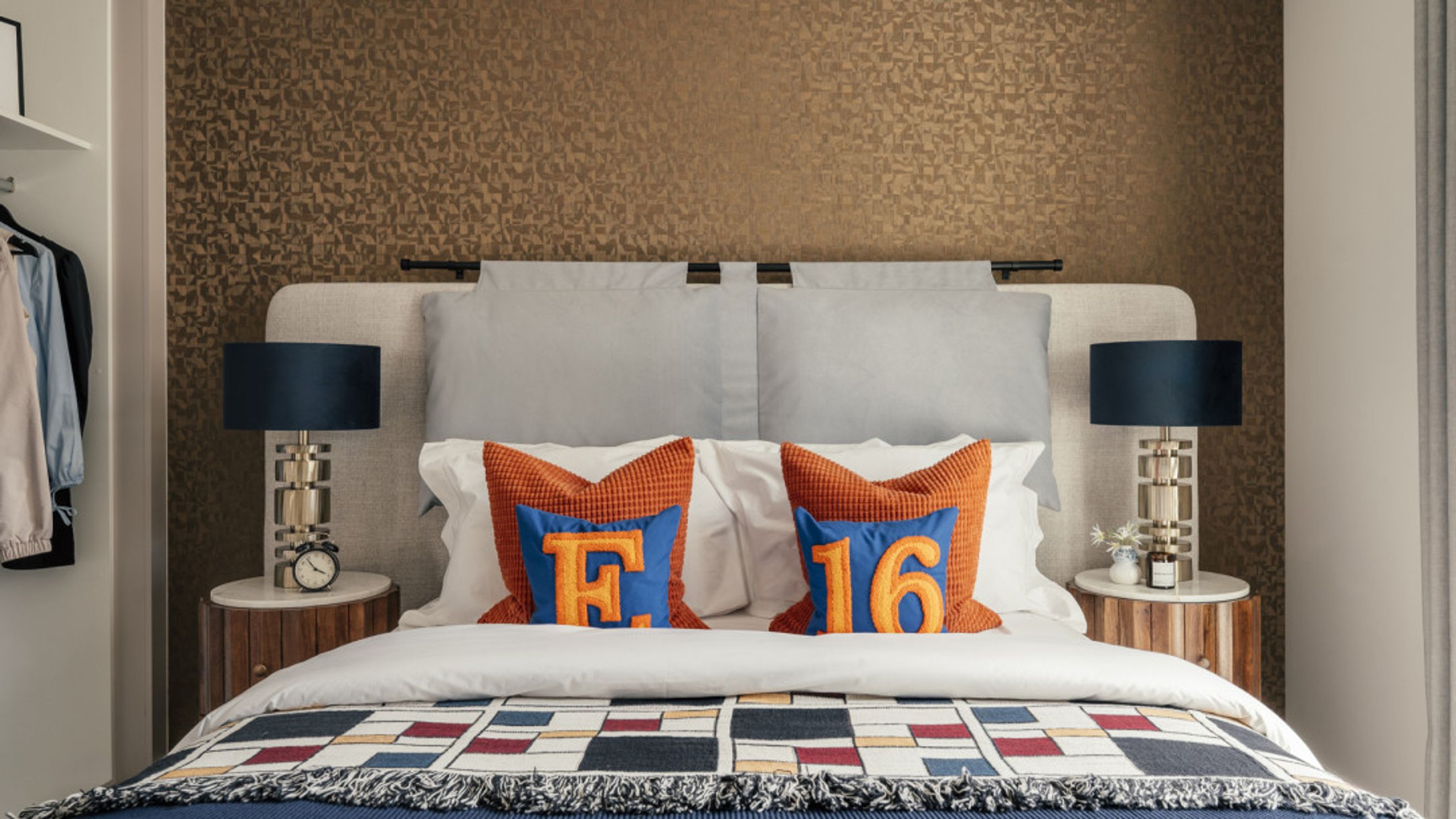 A bedroom with a bed, pillows, and bedside lamps.