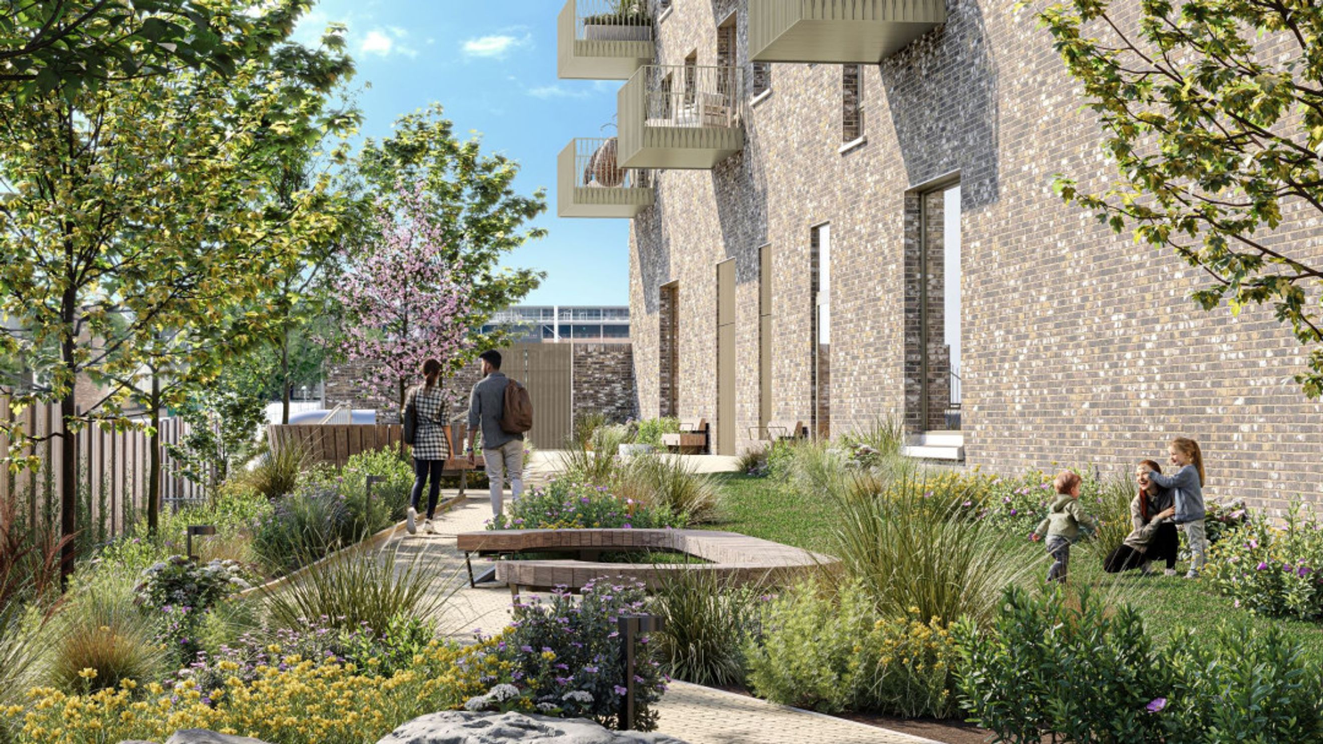 A landscaped garden with a water feature and people relaxing near a brick building.