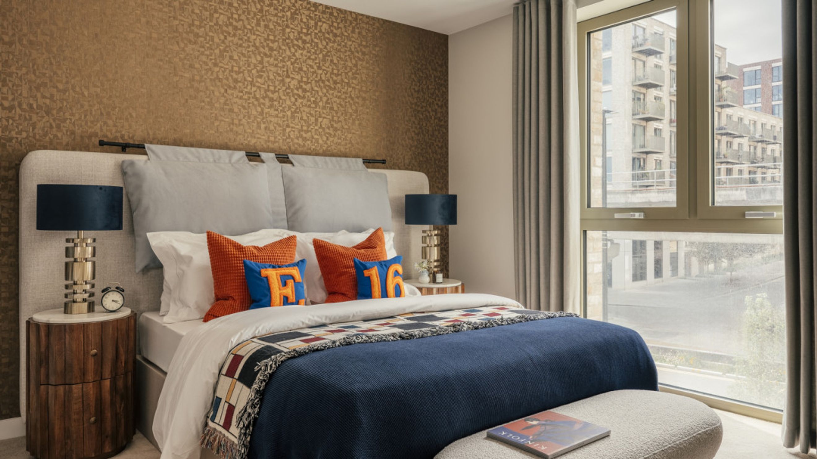 A bedroom with a bed, pillows, a nightstand, and a window.