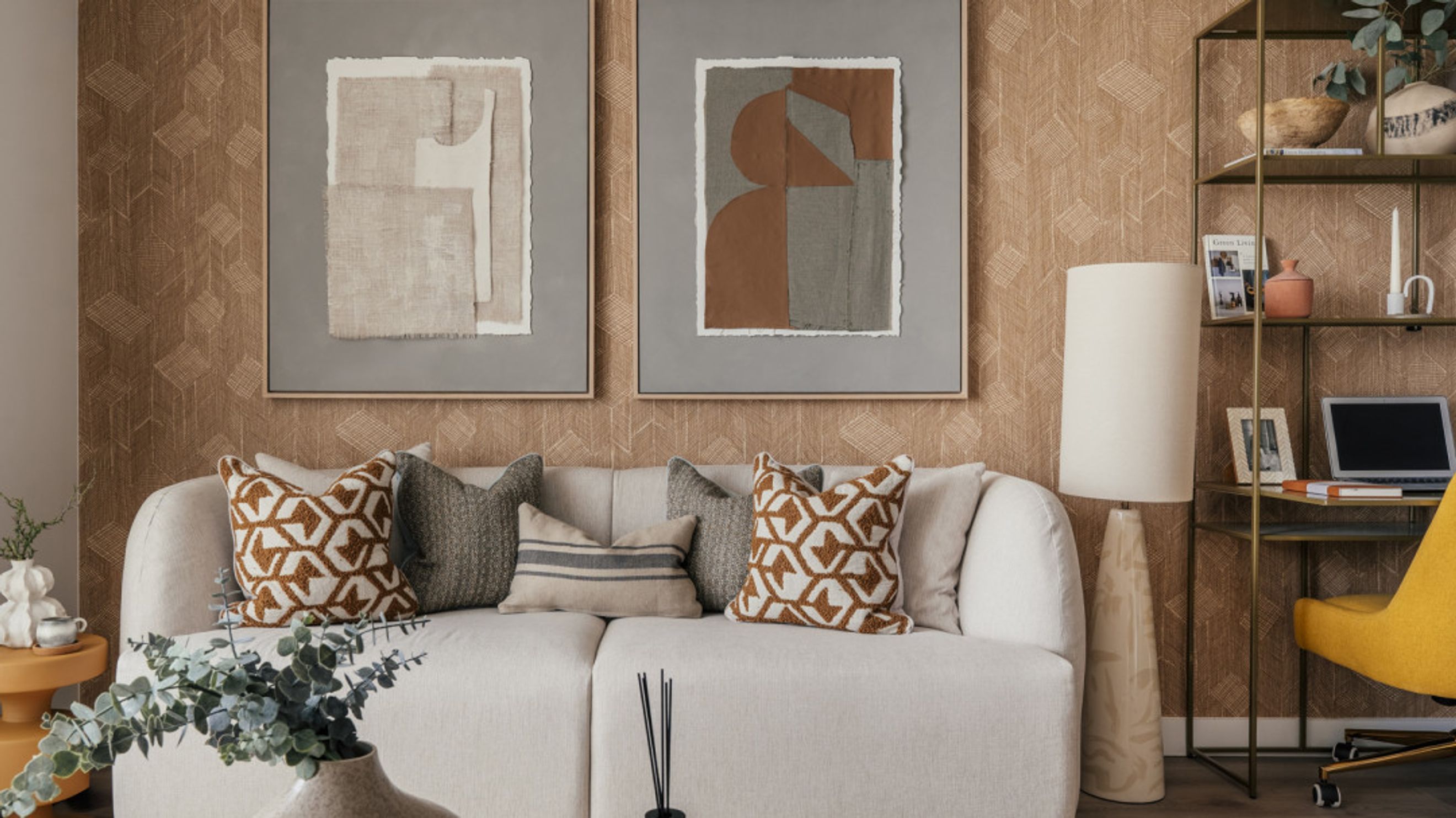 A living room with a sofa, pillows, artwork, and a floor lamp.